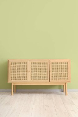 Yeşil duvarın yanındaki ahşap dolap.