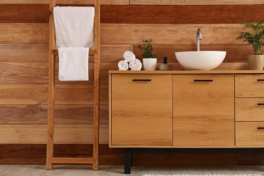 Tuvaletteki ahşap duvarın yanında lavabo ve havlular olan şık bir dolap.