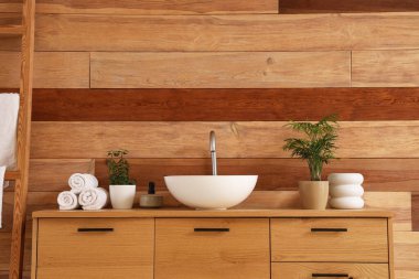 Banyoda ahşap duvarın yanında lavabo bulunan şık bir dolap.