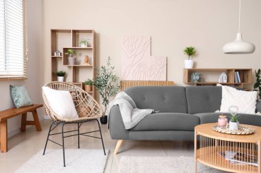 Siyah kanepesi, koltuğu, sehpası ve raf ünitesi olan şık bir oturma odası.