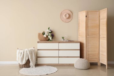 Çağdaş çekmecelerde, bej duvarın yanındaki odada leylakların olduğu çanta.