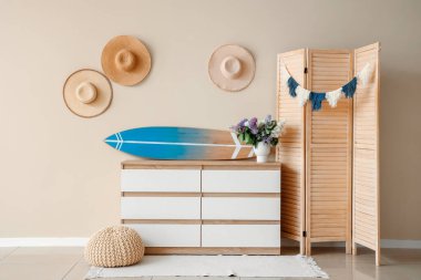 Modern çekmecelerde sörf tahtası ve odada bej duvarın yanında katlanan ekran.