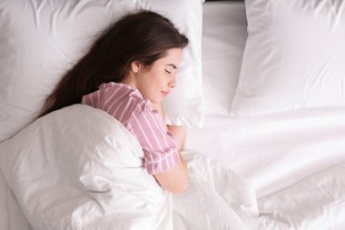 Güzel genç bir kadın rahat bir yatakta uyuyor.