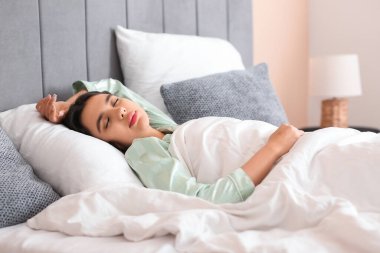 Evdeki yatak odasında uyuyan güzel genç bir kadın.