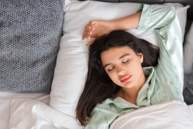 Evdeki yatak odasında uyuyan güzel, genç bir kadın.