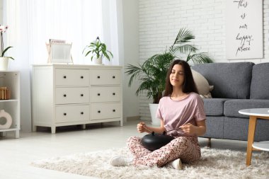 Oturma odasında yerde glukofon çalan genç bir kadın.