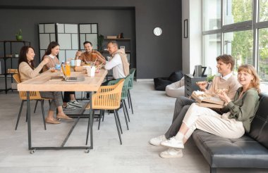 İş arkadaşları ofis mutfağında yemek yiyor.