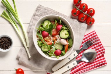 Beyaz ahşap arka planda turp ve domatesli taze sebze salatası.