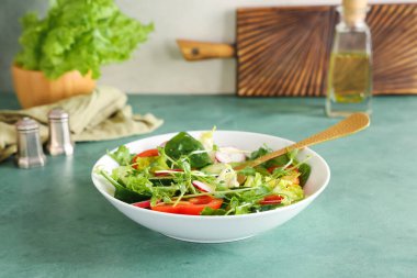 Bir kase taze sebze salatası ve turp yeşili masa.