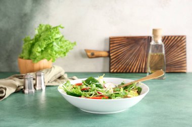 Bir kase taze sebze salatası ve turp yeşili masa.