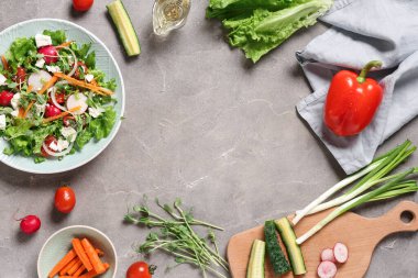 Feta peynirli taze salatadan yapılmış çerçeve ve gri arka planda farklı sebzeler.