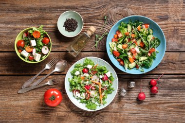 Tahta arka planda turplu ve peynirli taze sebze salatası.