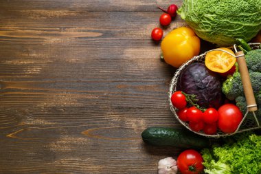 Tahta zemin üzerinde farklı taze sebzeler olan sepet.