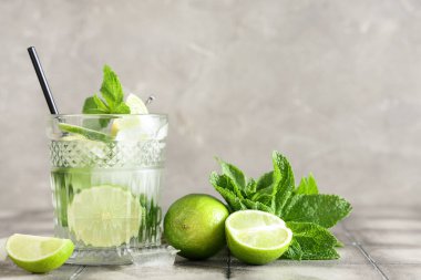 Bir bardak taze mojito kokteyli, limonlu ve naneli gri fayanslı.