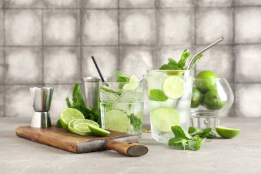 Gri masadaki limonlu ve naneli taze Mojito kokteyli.