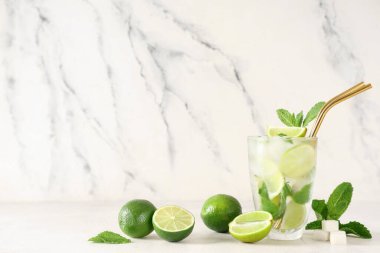 Beyaz arka planda limonlu, naneli ve şekerli bir bardak taze mojito kokteyli.