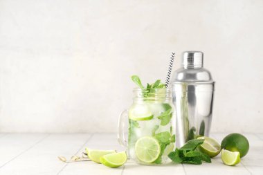 Mason kavanozu taze mojito kokteyli, limonlu ve sallanan beyaz fayanslı.