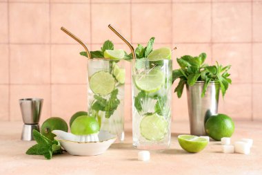 Bej masa üzerinde limon ve meyve sıkacağı ile taze Mojito kokteyli.