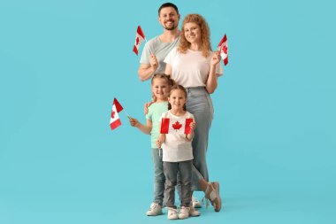 Mavi arka planda Kanada bayrakları olan mutlu güzel bir aile.