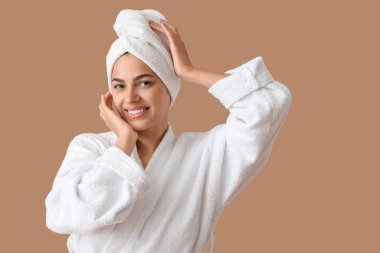 Bej arka planda havlusu olan bornozlu güzel, genç ve mutlu bir kadın.