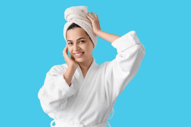 Mavi arka planda bornozlu güzel, genç, mutlu bir kadın.