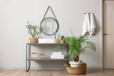 Lavabosu, çiçekleri ve havluları olan modern banyo.