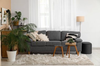 Siyah kanepesi, sehpası, çiçekleri ve tahtasıyla şık bir oturma odası.