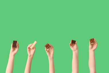 Yeşil arka planda farklı tatlı çikolataları olan kadın elleri.