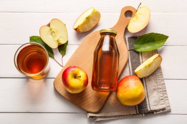 Beyaz ahşap arka planda bir şişe taze elma suyu.