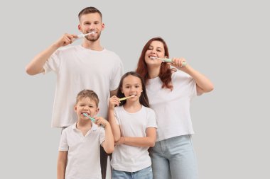 Mutlu aile arka planda dişlerini fırçalıyor.
