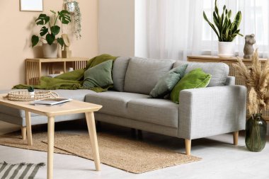 Gri kanepesi, masası ve yeşil bitkileri olan şık bir oturma odası.