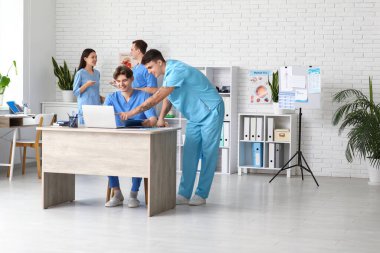 Klinikteki masada dizüstü bilgisayarla çalışan erkek doktorlar