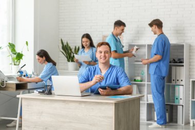 Klinikteki masada panosu olan bir erkek doktor.