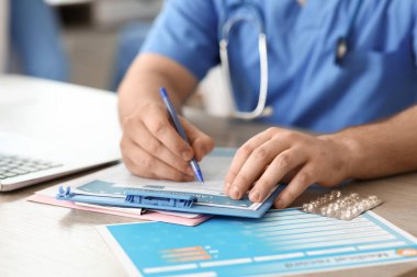 Klinikteki masada panoya yazı yazan erkek doktor, yakın plan.