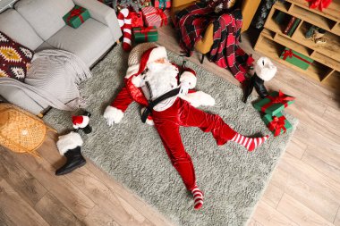 Şişeli sarhoş Noel Baba partiden sonra halıda uyuyor.