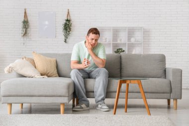 Bardaklı genç adam odada diş ağrısı çekiyor.