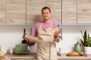 Evinde çiğ makarna kavanozu olan önlüklü genç adam.