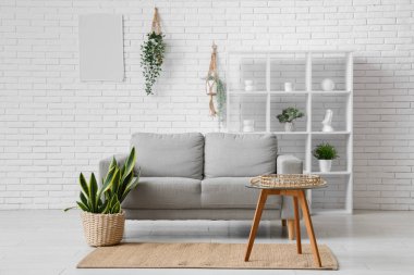 Gri kanepesi, sehpası ve raf ünitesi olan bir oturma odası.