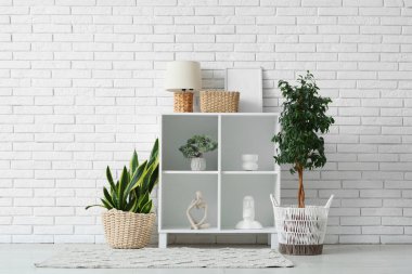 Ev bitkisi, heykel ve raf üniteli aydınlatma odasının içinde.