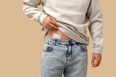 Bej arka planda apandisit ameliyatı geçirmiş genç bir adam, yakın plan.