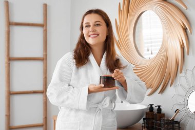 Banyoda anti-selülit fırçası olan güzel, iri yarı bir kadın.