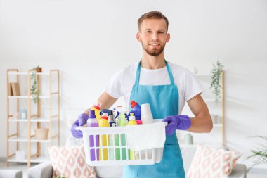 Işık odasında temizlik malzemesi sepeti olan bir erkek hademe.