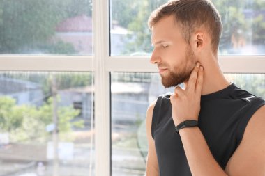 Sportif genç adam pencerenin yanındaki nabzını kontrol ediyor, yakın plan.