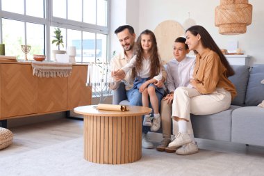 Evdeki kanepesinde menoralı mutlu Yahudi bir aile.