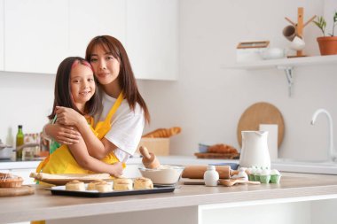 Mutlu Asyalı anne ve küçük kızı mutfakta tarçınlı rulo pişiriyorlar.