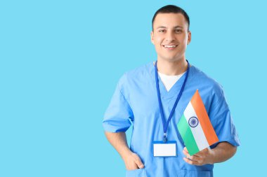 Mavi arka planda Hindistan bayrağı olan erkek doktor. Ulusal Doktorların Günü kutlaması