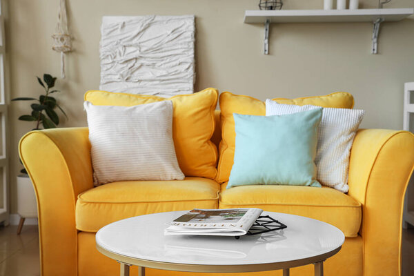 Stylish living room with yellow sofa, pillows and coffee table