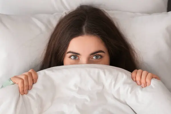 Stock image Pretty young woman lying in cozy bed