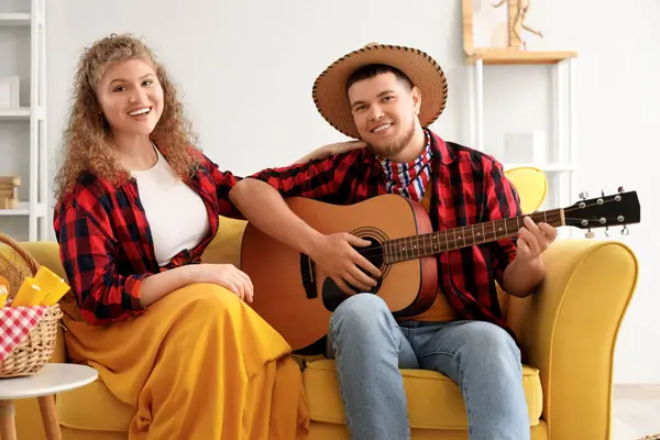 stock image Happy young couple with guitar sitting on sofa at home. Festa Junina celebration