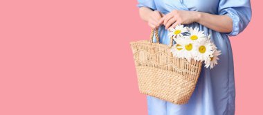 Elinde papatya çiçekli hasır çanta ve pembe arka planda mesaj için yeri olan genç bir kadın.